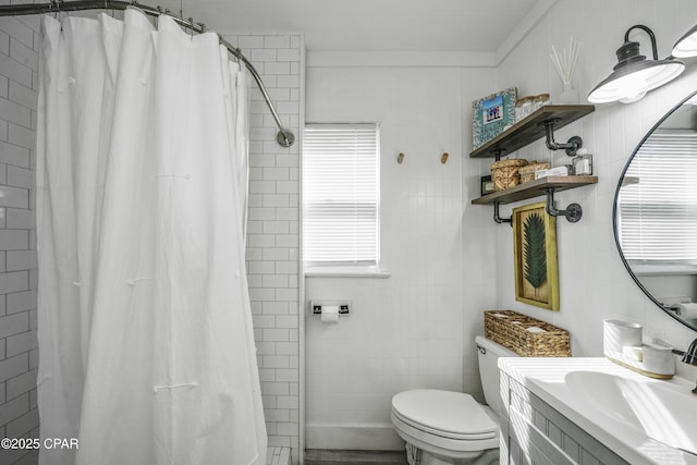 bathroom with a wealth of natural light, curtained shower, tile walls, vanity, and toilet