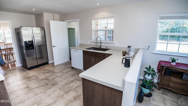 kitchen with sink, white dishwasher, stainless steel fridge with ice dispenser, and dark brown cabinets