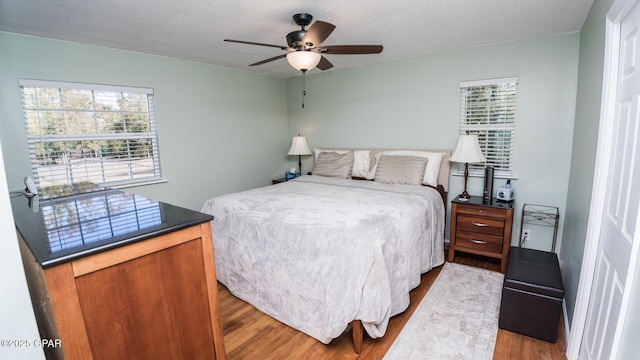 bedroom featuring multiple windows, wood-type flooring, and ceiling fan