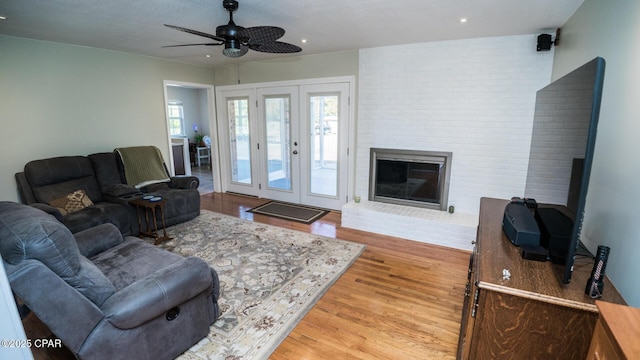 living room featuring wood-type flooring, a healthy amount of sunlight, ceiling fan, and a fireplace