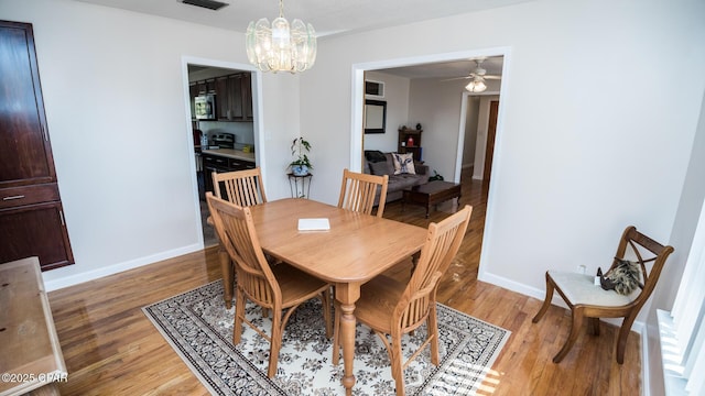 dining room with ceiling fan with notable chandelier and wood-type flooring