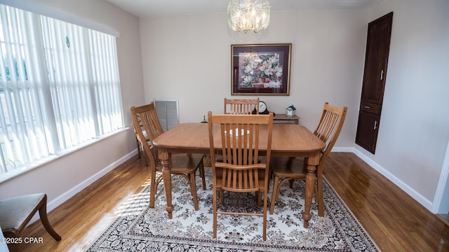 dining area featuring hardwood / wood-style flooring and a notable chandelier