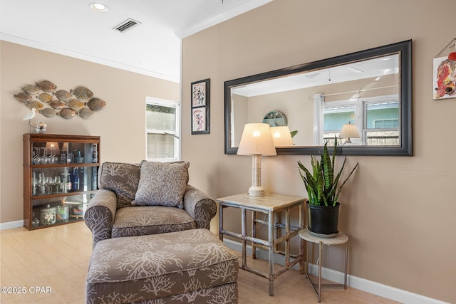 living area featuring ornamental molding, a healthy amount of sunlight, and light wood-type flooring