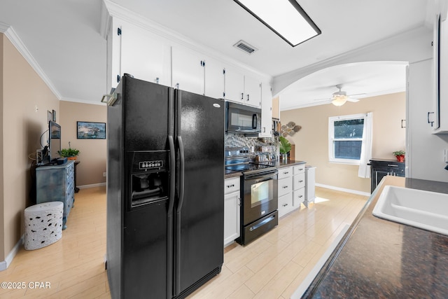 21823 Marlin Ave, Panama City Beach, FL 32413 - kitchen featuring black appliances, arched walkways, crown molding, white cabinets, and baseboards