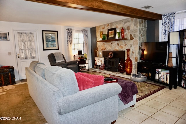 living room with light tile patterned flooring, a wood stove, and beam ceiling