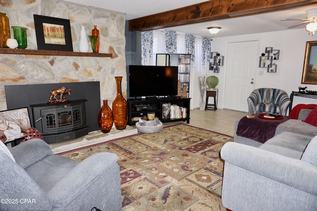 living room with ceiling fan, tile patterned floors, beam ceiling, and a wood stove