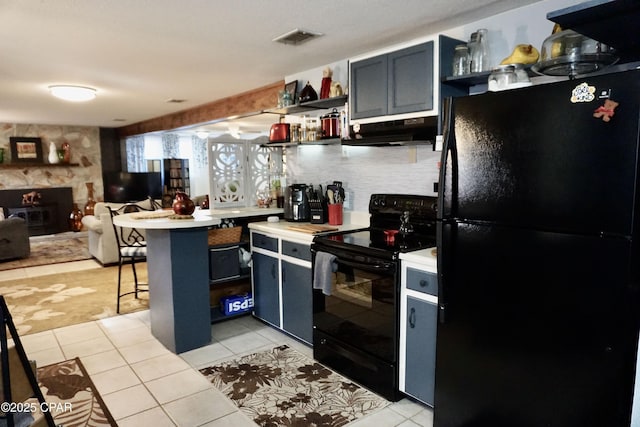 kitchen with light tile patterned floors, a fireplace, black appliances, and a kitchen breakfast bar