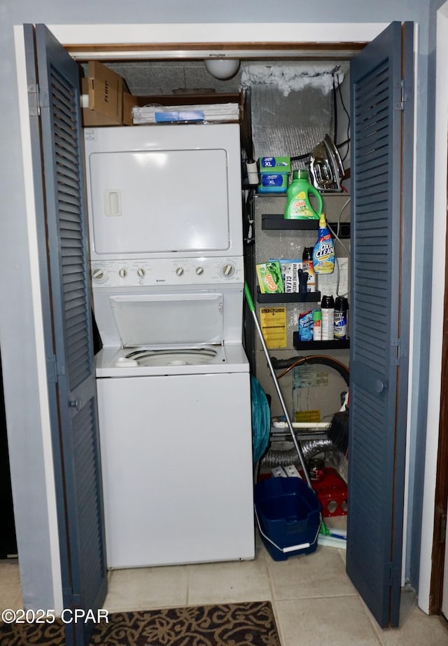 clothes washing area with light tile patterned floors and stacked washer and clothes dryer