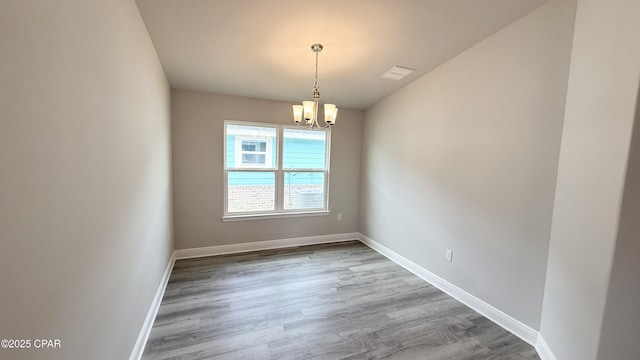 spare room with hardwood / wood-style flooring and a chandelier