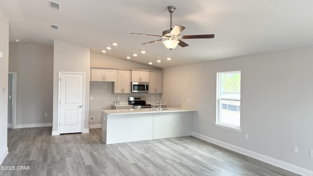 kitchen with lofted ceiling, sink, white cabinetry, light wood-type flooring, and appliances with stainless steel finishes