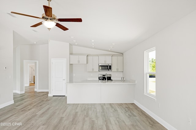 1202 Danley St, Panama City, FL 32404 - kitchen with stainless steel microwave, vaulted ceiling, light countertops, white cabinetry, and stove