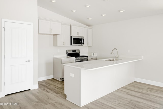 1202 Danley St, Panama City, FL 32404 - kitchen featuring a sink, appliances with stainless steel finishes, a peninsula, light wood-style floors, and vaulted ceiling