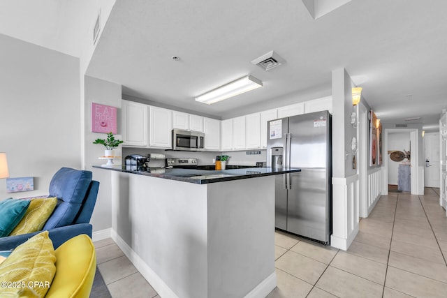 kitchen featuring light tile patterned flooring, stainless steel appliances, kitchen peninsula, and white cabinets