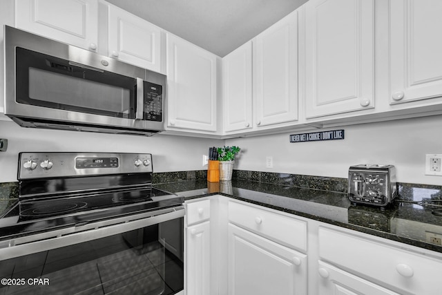 kitchen with white cabinetry, stainless steel appliances, and dark stone counters