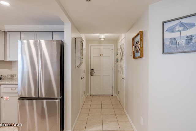 kitchen featuring stainless steel fridge, light stone countertops, and light tile patterned flooring