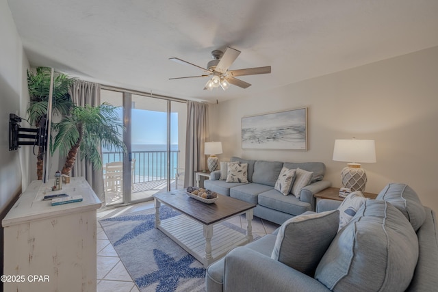 living room with a wall of windows, light tile patterned flooring, ceiling fan, and a water view