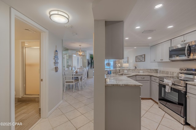 kitchen with sink, light tile patterned floors, appliances with stainless steel finishes, light stone counters, and kitchen peninsula