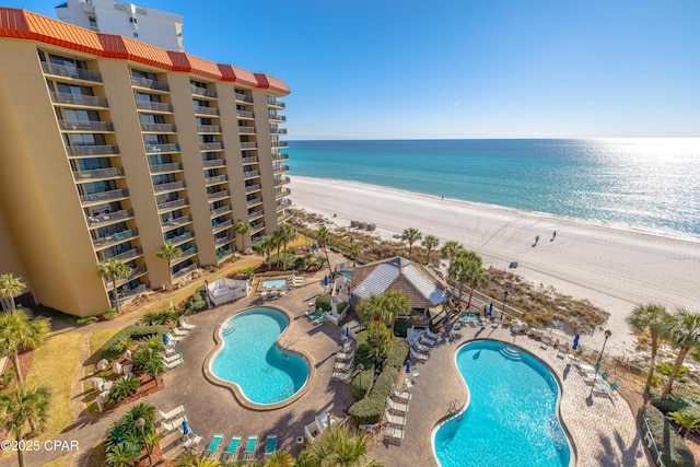 view of swimming pool with a water view, a beach view, and a patio area