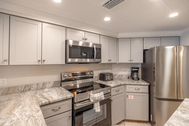 kitchen with light tile patterned floors, crown molding, gray cabinets, appliances with stainless steel finishes, and light stone countertops