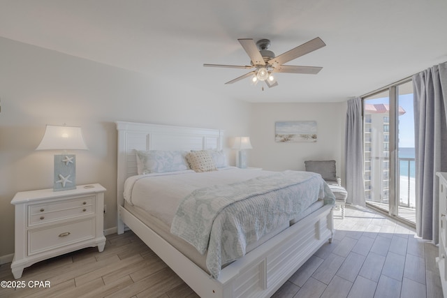 bedroom featuring access to outside, floor to ceiling windows, ceiling fan, and a water view