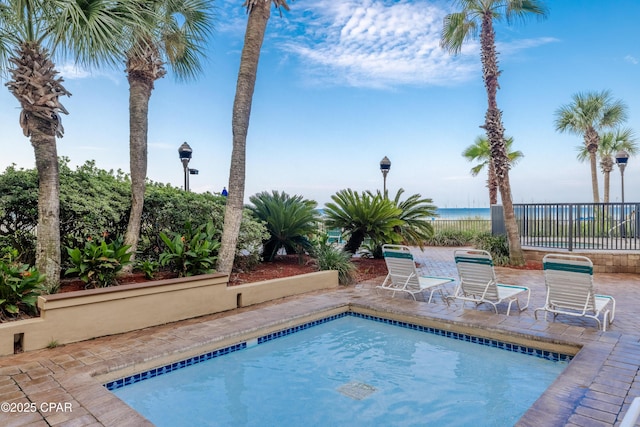 view of pool featuring a water view and a patio