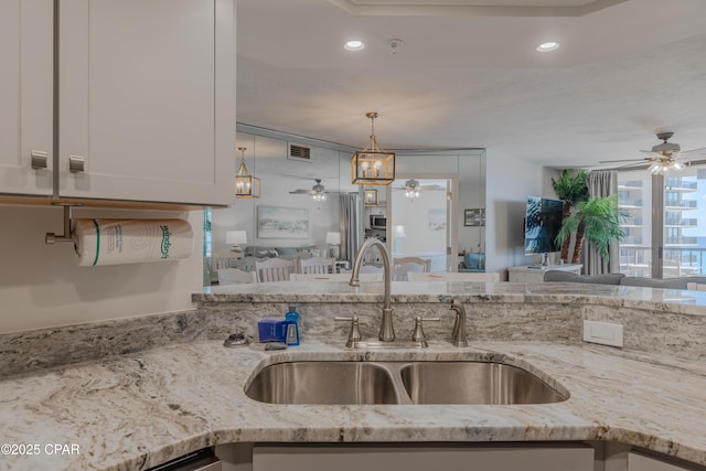 kitchen with white cabinetry, light stone countertops, sink, and ceiling fan