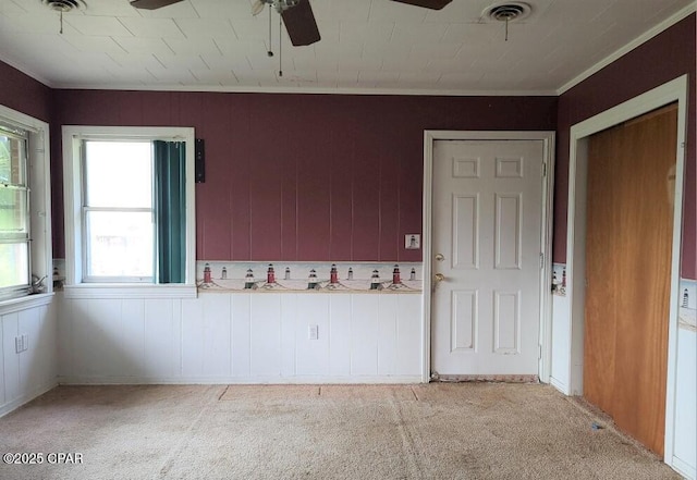 unfurnished room with crown molding, light colored carpet, and ceiling fan