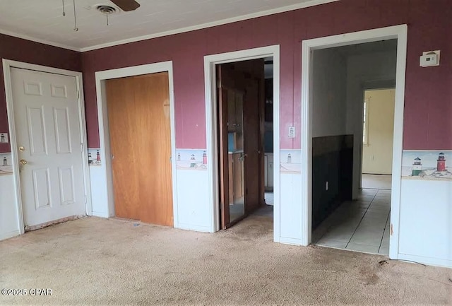 unfurnished bedroom featuring crown molding, ensuite bath, and light colored carpet