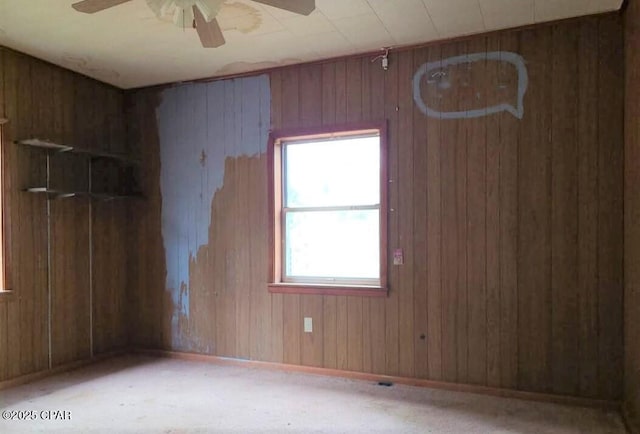 empty room with ceiling fan and wood walls