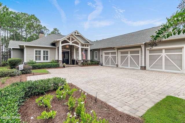 22207 Fox Glenn Trce, Panama City Beach, FL 32413 - craftsman house featuring decorative driveway, a garage, a chimney, a shingled roof, and covered porch
