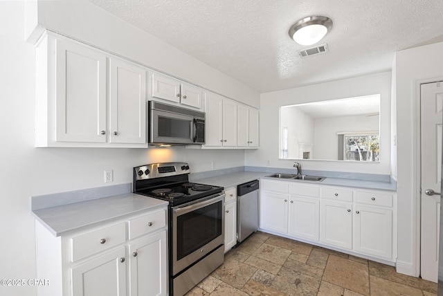 kitchen featuring white cabinetry, stainless steel appliances, sink, and a textured ceiling