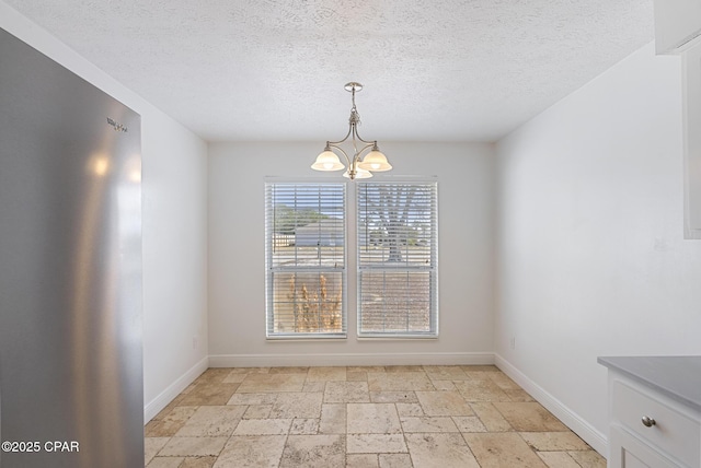 unfurnished dining area with a textured ceiling and a chandelier