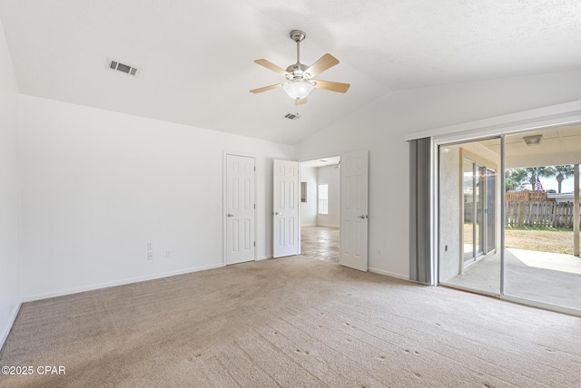 empty room featuring light carpet, vaulted ceiling, and ceiling fan