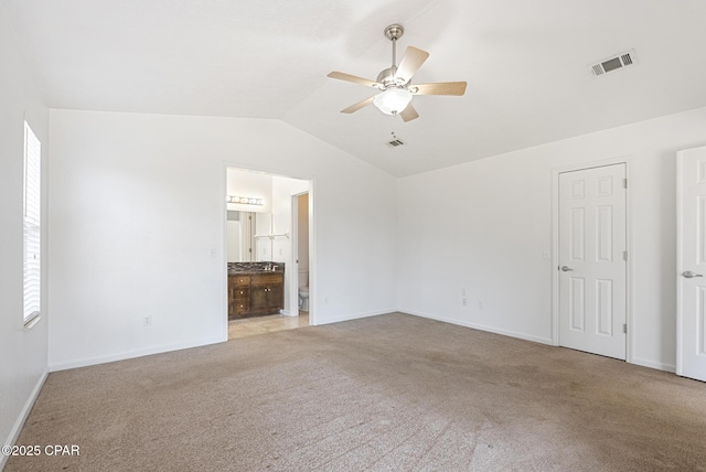 interior space with vaulted ceiling, light colored carpet, and ceiling fan