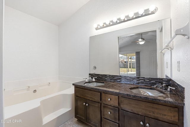 bathroom featuring tasteful backsplash, vanity, vaulted ceiling, and a washtub