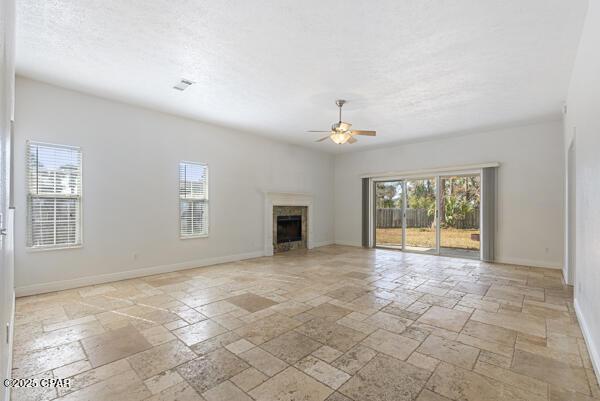 unfurnished living room with a healthy amount of sunlight, a textured ceiling, and ceiling fan