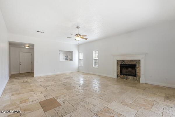 unfurnished living room with ceiling fan and a fireplace