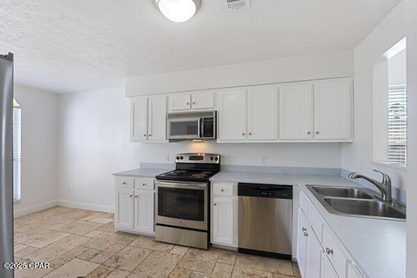 kitchen featuring sink, a textured ceiling, white cabinets, and appliances with stainless steel finishes