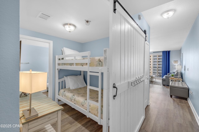 bedroom with a barn door and hardwood / wood-style floors