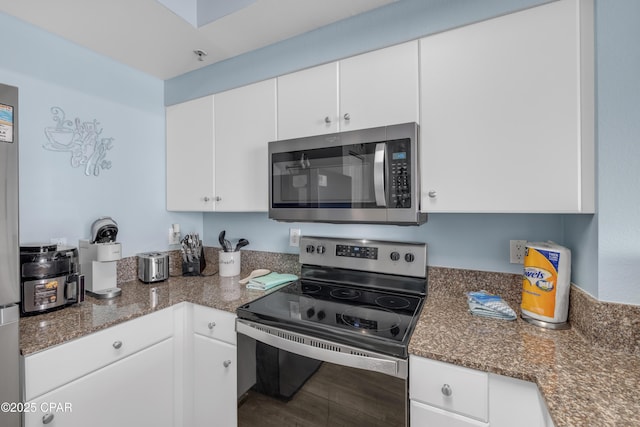 kitchen with stainless steel appliances, wood-type flooring, white cabinets, and dark stone counters