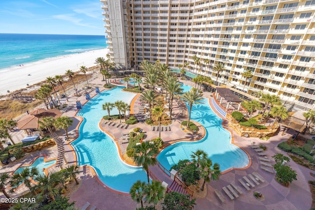 view of swimming pool featuring a view of the beach, a patio area, and a water view