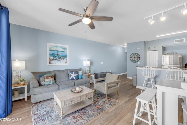 living room featuring light hardwood / wood-style floors, rail lighting, and ceiling fan