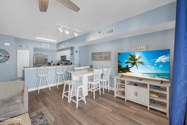 dining space with wood-type flooring, ceiling fan, and track lighting