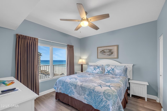 bedroom with a water view, ceiling fan, and hardwood / wood-style flooring