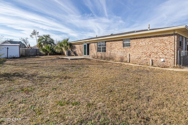 back of property with a yard, fence, and brick siding