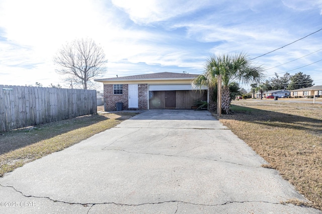 view of front of home with concrete driveway, a front lawn, an attached garage, brick siding, and fence