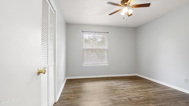 unfurnished bedroom with dark wood-type flooring, ceiling fan, a closet, and a textured ceiling