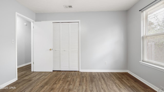 unfurnished bedroom featuring dark hardwood / wood-style flooring and a closet