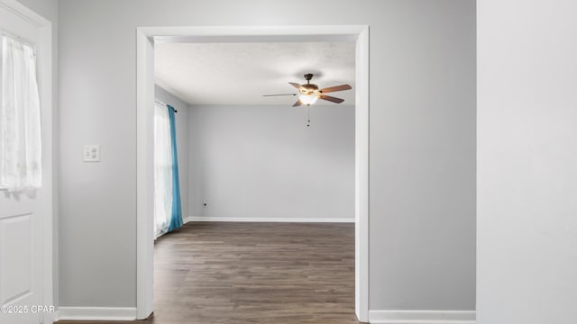 empty room with ceiling fan, dark wood-type flooring, and a textured ceiling