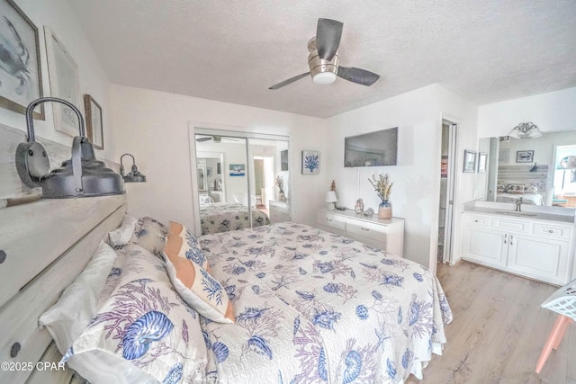 bedroom with ceiling fan, sink, a textured ceiling, and light hardwood / wood-style floors